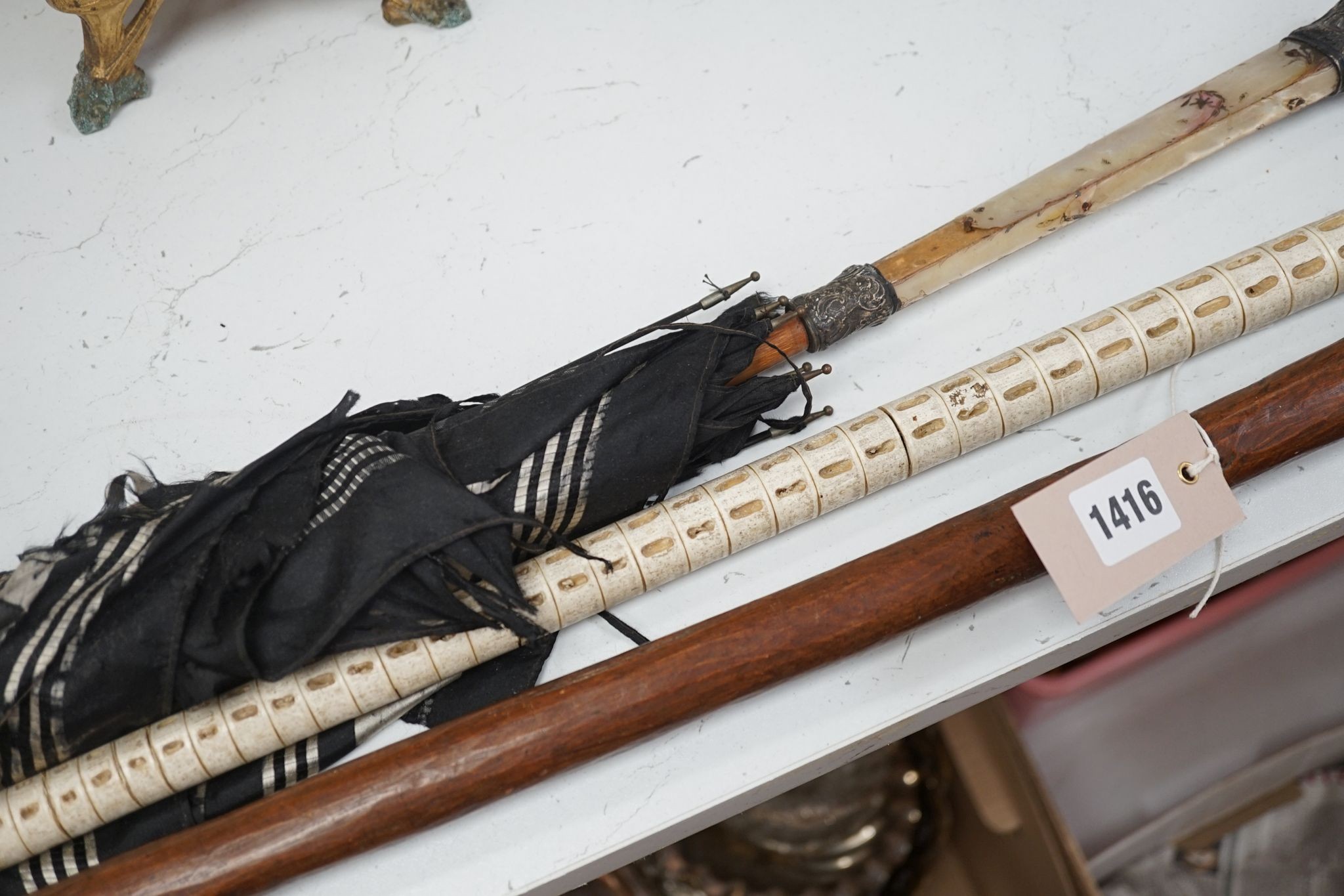 A carved wood figural walking cane, a vertebrae walking stick and a Victorian parasol. Longest 108cm